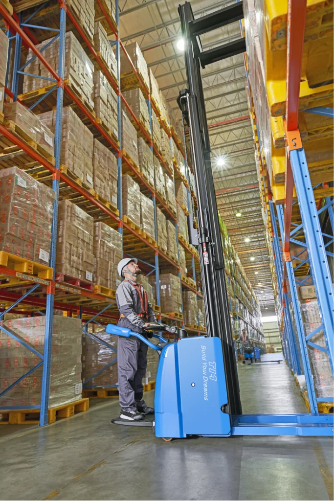 A man organizing the shelves with the help of a forklift
